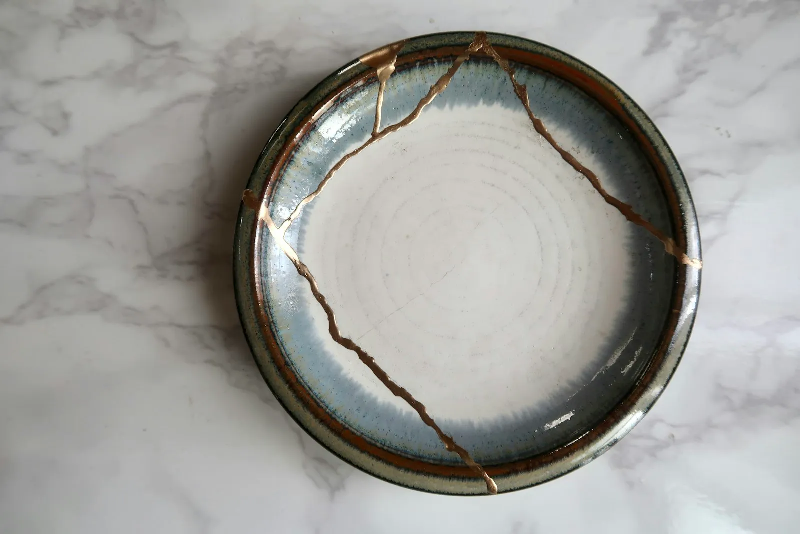 Farfurie ceramică reparată prin tehnica kintsugi, cu fisurile umplute cu aur